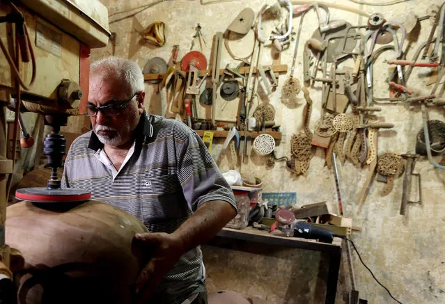 In this photo taken Saturday, June 20, 2015, Mahmoud Abdulnabi builds an oud at his workshop in Baghdad, Iraq. Iraq is widely believed to be the birthplace of the oud, an ancestor of the guitar and a central instrument in Middle Eastern music. The oldest known image of an oud is a 5,000-year stone carving found in southern Mesopotamia depicting a woman strumming the instrument on a boat. (Photo by Hadi Mizban/AP Photo)