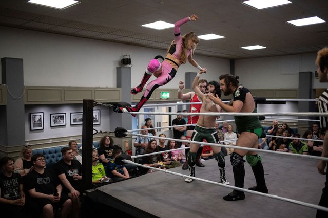 Professional wrestler Kiya (L) leaps onto fellow wrestlers Nishiki (2nd R) and Lewis Johnson (R) during a tag-team bout during an evening of wrestling entertainment presented by promoter “Off The Page” in St Benedict's Social Club in Warrington, northwest England, on May 18, 2024. (Photo by Oli Scarff/AFP Photo)