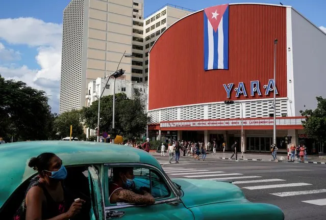 People walk in front of the Yara cinema on the opening day of the International Festival of New Latin American Cinema, in Havana, Cuba on December 4, 2021. (Photo by Natalia Favre/Reuters)