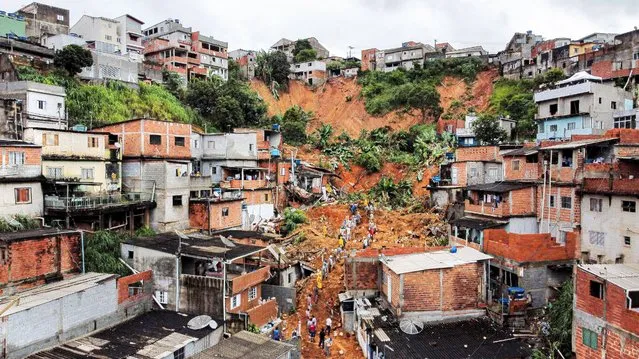 General view of citizens helping firefighters remove mud in search of victims after a landslide caused by heavy rains buried homes in Franco da Rocha, Sao Paulo state, Brazil, on January 31, 2022. Torrential rains in Brazil's Sao Paulo state between Friday and Sunday left at least 18 people dead, authorities said. (Photo by Filipe Araujo/AFP Photo)