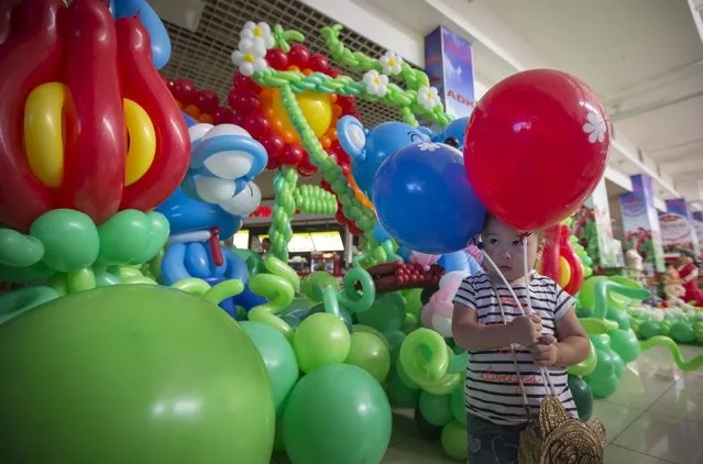 A girl holds balloons as she visits an international festival of air balloons design in Almaty, Kazakhstan, July 9, 2015. (Photo by Shamil Zhumatov/Reuters)