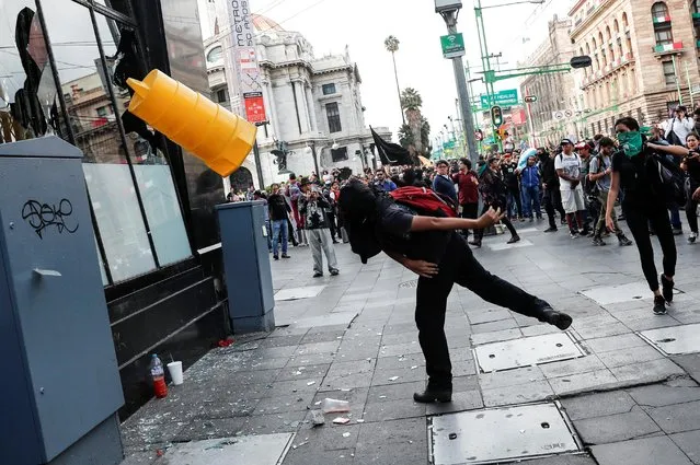 A protester flings an object at a building as people march to mark the fifth year since the disappearance of the 43 students of the Ayotzinapa Teacher Training College in the state of Guerrero, in Mexico City, Mexico on September 26, 2019. (Photo by Carlo Jasso/Reuters)