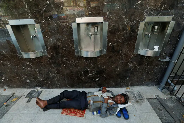 A man sleeps next to drinking water taps on a hot summer afternoon in Mumbai, India May 9, 2016. (Photo by Danish Siddiqui/Reuters)