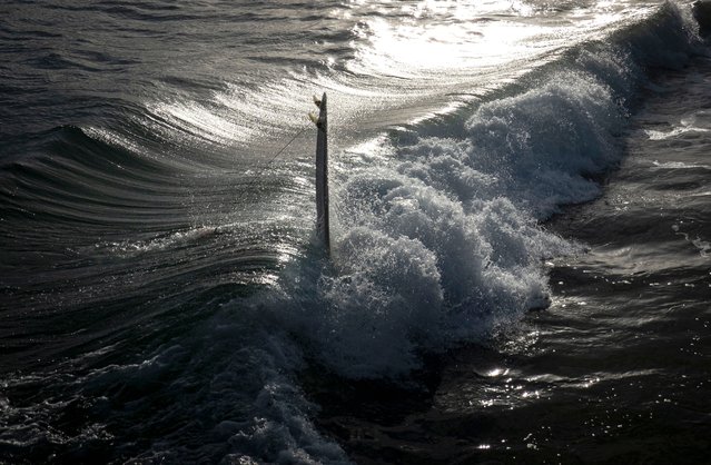 A man falls from his surfing board as he gets knocked by a wave in San Sebastian, Spain, 10 April 2024. (Photo by Javier Etxezarreta/EPA/EFE)