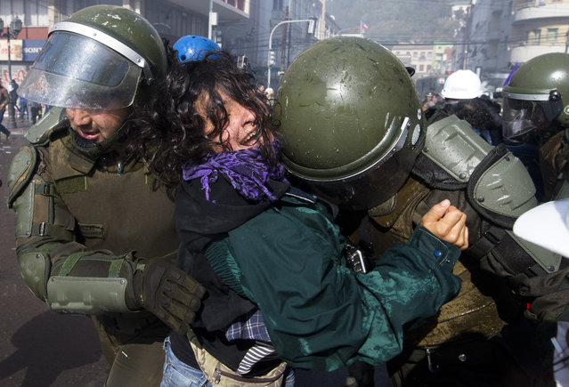 A woman is detained by riot police during a protest turned violent near Congress, where President Michelle Bachelet was presenting the state-of-the-nation report, in Valparaiso, Chile, Saturday, May 21, 2016. The anti-government protest that began as a peaceful march turned rough as some demonstrators threw rocks at police and gasoline bombs at buildings, resulting in the death of one man who reportedly died of asphyxiation. (AP Photo/Esteban Felix)