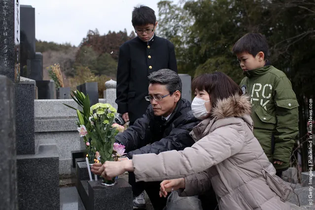 Keiko Takeda, husband Yoshihiro and two son's Seiya and Shunma place flowers at the gravesite of her parents, Tetsji and Hiroko and uncle Hiroo and aunt Moto at the Jodoji Temple on March 11, 2012 in Rikuzentakata, Japan