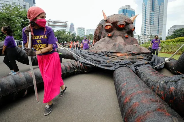 An activist pulls a puppet depicting the “oligarchy octopus monster” while taking part in a rally to support women's rights calling for gender equality and to protest against gender discrimination, during the International Women's Day outside the National Monument (Monas) complex in Jakarta, Indonesia, March 8, 2022. (Photo by Willy Kurniawan/Reuters)