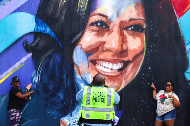 A Chicago police officer takes a picture of people posing before a mural of Democratic presidential nominee US Vice President Kamala Harris outside the United Center ahead of the Democratic National Convention (DNC) in Chicago, Illinois on August 17, 2024. The mural, created by Ian Robertson and Salt and Pique Brown, was commissioned by Emily’s List in 2020 Vice President Kamala Harris will formally accept the party’s nomination for president at the DNC which runs from August 19-22 in Chicago. (Photo by Charly Triballeau/AFP Photo)