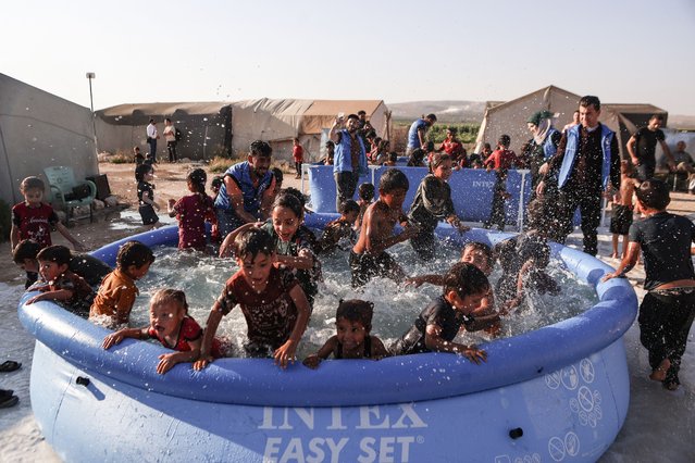 Displaced Syrian children play in a mobile swimming pool set up by the Smile Younited charity organisation, during the sweltering summer heat in the Kafr Naseh camp, in the rebel-held part of Aleppo province on July 27, 2024. The pools at the camp for displaced people provided rare entertainment to young boys and girls whose lives have been scarred by war and poverty. (Photo by Aaref Watad/AFP Photo)