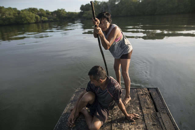 Carmen Garcia paddles a raft as she and her long-time boyfriend Juan Carlos Pirela start collecting their fish nets in hopes of a catch for food to eat in Lake Maracaibo in Cabimas, Venezuela, November 25 2019. For many in Maracaibo, Venezuela's economic crash in the last five years hit especially hard. Once a center of the nation's vast oil wealth, production under two decades of socialist rule has plummeted to a fraction of its high, taking down residents' standard of living. (Photo by Rodrigo Abd/AP Photo)