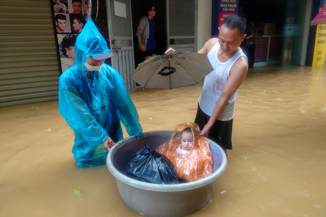 A boy sits in a floating basket as people wade through a flooded street following the impact of Typhoon Yagi, in Hanoi, Vietnam, on September 11, 2024. (Photo by Khanh Vu/Reuters)