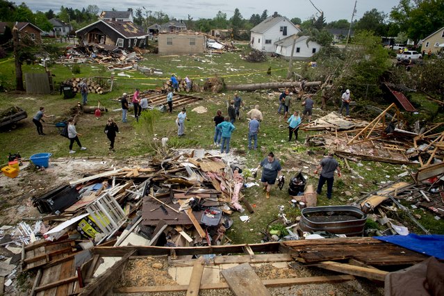 More than two dozen community members pull together to clean up the devastating aftermath at the home of Steve and Theresa Haskes in Gaylord, Mich., on Saturday, May 21, 2022, after an EF3 tornado ripped through the small northern Michigan city. (Photo by Jake May/The Flint Journal via AP Photo)