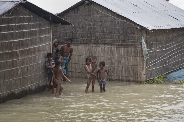Indian villagers stand outside their houses partially submerged in flood waters in Burgaon, 80 kilometers (50 miles) east of Gauhati, Assam state, India, Wednesday, July 5, 2017. Heavy rains since the start of India's monsoon season have triggered floods and landslides in parts of the remote northeastern region, causing at least 20 deaths, authorities said Wednesday. (Photo by Anupam Nath/AP Photo)