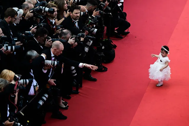 A young guest pose in front of photographers on the red carpet before the screening of “Final Cut (Coupez !)” ahead of the opening ceremony of the 75th edition of the Cannes Film Festival in Cannes, southern France, on May 17, 2022. (Photo by Antonin Thuillier/AFP Photo)