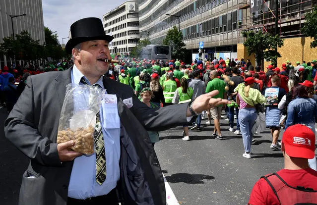 A man wearing a top hat throws peanuts as he marches with trade unions during a demonstration to protest against the rising cost of living in Brussels, Monday, June 20, 2022. (Photo by Geert Vanden Wijngaert/AP Photo)