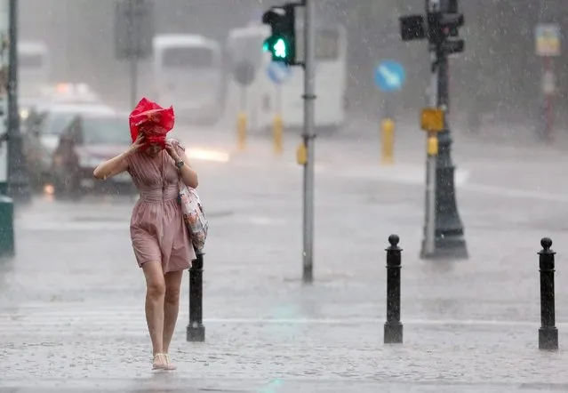 A woman tries to protect her hair from the rain during a downpour in Warsaw, Poland, 26 June 2016. (Photo by Pawel Supernak/EPA)