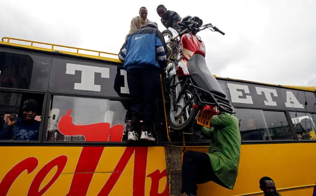 Loaders push a motorcycle atop a public bus for passengers traveling to the countryside ahead of next week's general election in Nairobi, Kenya on August 3, 2017. (Photo by Thomas Mukoya/Reuters)