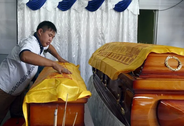 A family member places a cloth over 4-year-old Lee Jing Xuan's coffin, after she and her father Lee Tze Siang were killed in Monday's deadly blast in Bangkok, Thailand, at their home in Butterworth, Malaysia, August 20, 2015. (Photo by Olivia Harris/Reuters)