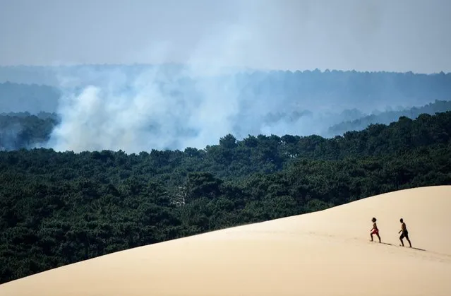People walk on the Dune of Pilat (Dune du Pilat) near La Teste-de-Buch, southwestern France, on July 16, 2022. The intense mobilization of firefighters did not weaken on July 16, 2022 to fix the fires in the south of France, and particularly in Gironde where new evacuations are in progress in front of the advance of the flames which ravaged more than 10.000 hectares of forests, in a context of generalized heat wave all weekend. (Photo by Gaizka Iroz/AFP Photo)