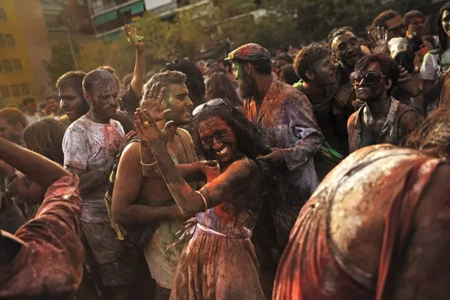 Revelers of the Holi Festival of Colors dance after throwing colored powders in the air in Madrid, Spain, Saturday, August 9, 2014. The festival is fashioned after the Hindu spring festival Holi, which is mainly celebrated in the north and east areas of India. (Photo by Daniel Ochoa de Olza/AP Photo)
