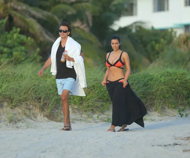 Kim Kardashian surfs up an impressive sight as she wanders along a Miami beach in a colourful bikini on August 4, 2012. The reality TV star looked stunning as she wandered barefoot along the shore in the black and orange two-piece
