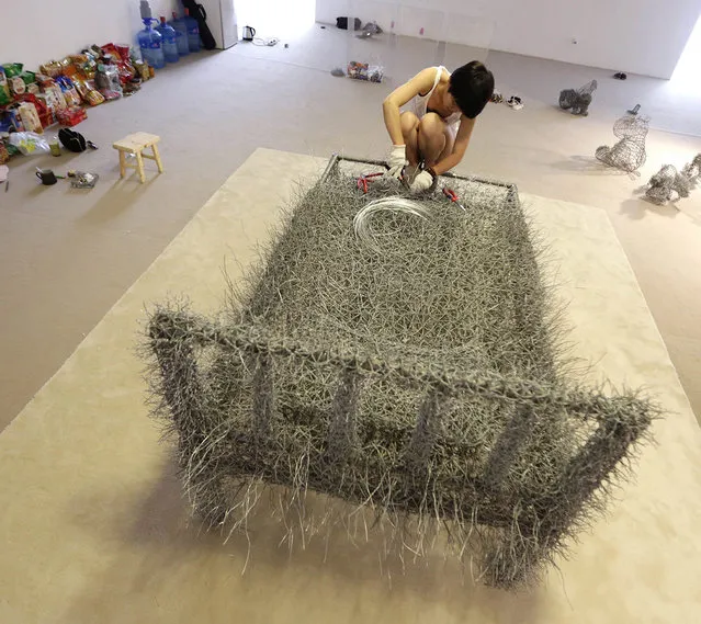 Chinese artist Zhou Jie works on an iron wire bed, which she sleeps on for her art project “36 Days”, next to food (L) and her other sculpture works (R) at Beijing Now Art Gallery, in Beijing August 11, 2014. (Photo by Jason Lee/Reuters)