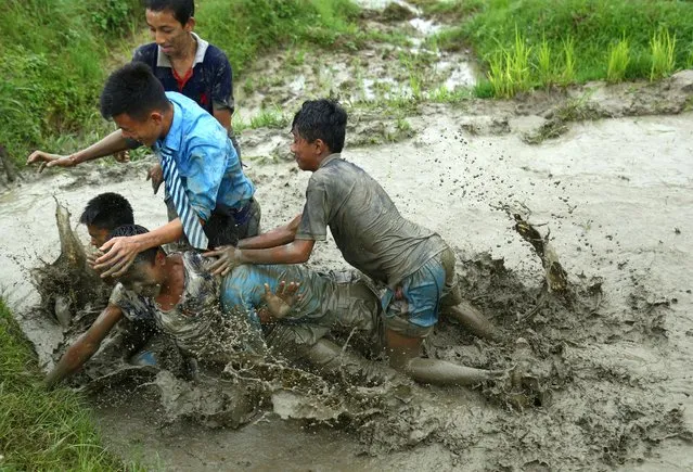 Students play in mud as they plant rice samplings on the field during National Paddy Day, also called Asar Pandra, that marks the commencement of rice crop planting in paddy fields as monsoon season arrives, in Kathmandu, Nepal on June 29, 2022. (Photo by Dipen Shrestha/ZUMA Press Wire/Rex Features/Shutterstock)