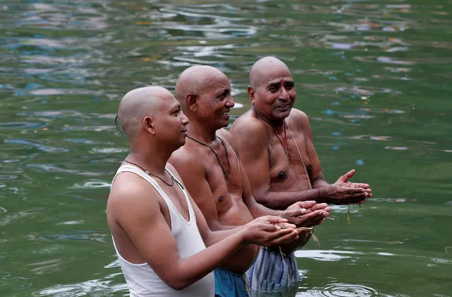 Hindus pray as they take a dip in the waters of holy Banganga Tank to honour the souls of their departed ancestors on the auspicious day of Mahalaya in Mumbai, September 19, 2017. (Photo by Shailesh Andrade/Reuters)