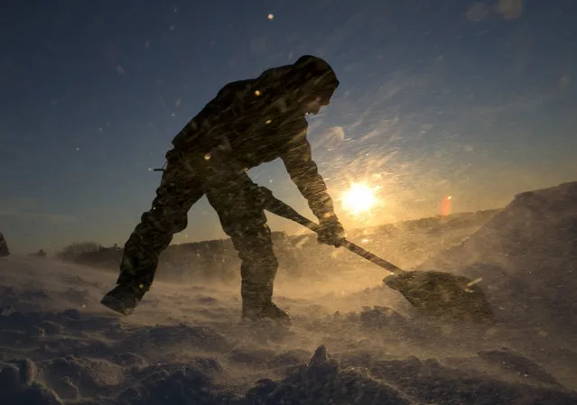 Fierce winds blow snow as snowboarder Garrett Ramos, 20, uses a shovel to build a jump, Friday, January 3, 2014, in Portland, Maine. (Photo by Robert F. Bukaty/AP Photo)