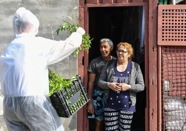 A Romanian Christian Orthodox priest, with a face mask, distributes willow branches on the Easter Sunday on April 12, 2020 after a religious service held within closed doors due to the social distancing rules amid the spread of the coronavirus pandemic. (Photo by Daniel Mihailescu/AFP Photo)