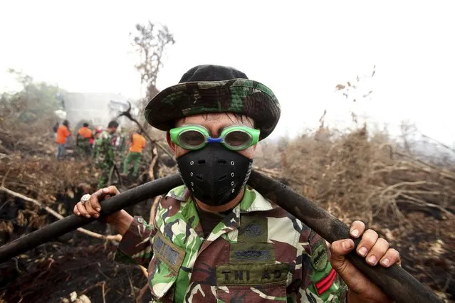 An Indonesian soldier uses swimming goggles to protect his eyes from smoke while helping to fight a fire in a peatland forest area in Parit Indah Village, Kampar, Riau province, Indonesia September 8. 2015. Seasonal forest fires have covered large parts of the island of Sumatra and Kalimantan in smoke and haze. (Photo by Y. T. Haryono/Reuters)