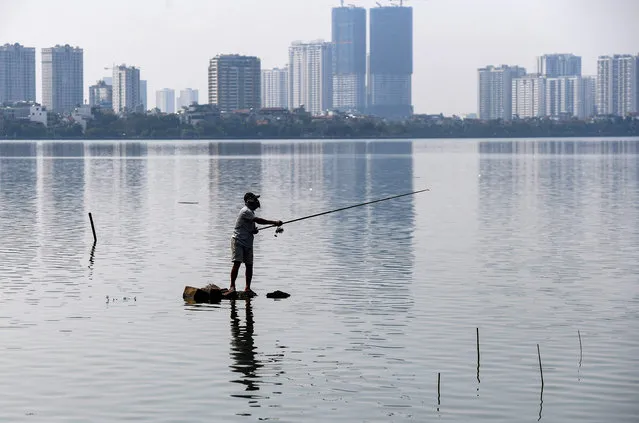 A man fishes at West Lake, the largest freshwater lake in Hanoi, on September 19, 2022. (Photo by Nhac Nguyen/AFP Photo)