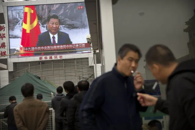 Men light cigarettes as a television screen outside of the Beijing Railway Station shows a live broadcast of Chinese President Xi Jinping introducing members of the Politburo Standing Committee of China's 19th Party Congress at the Great Hall of the People in Beijing, Wednesday, October 25, 2017. Communist Party leader Xi Jinping on Wednesday unveiled the lineup of the party's highest body who will rule alongside him as he embarks on a second five-year term as party leader. (Photo by Mark Schiefelbein/AP Photo)