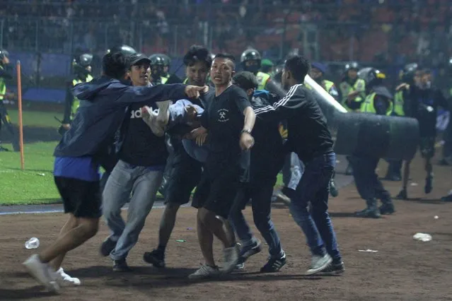 Supporters evacuate a man hit by tear gas fired by police during the riot after the league BRI Liga 1 football match between Arema vs Persebaya at Kanjuruhan Stadium, Malang, East Java province, Indonesia on October 2, 2022, in this photo taken by Antara Foto. (Photo by Ari Bowo Sucipto/Antara Foto via Reuters)