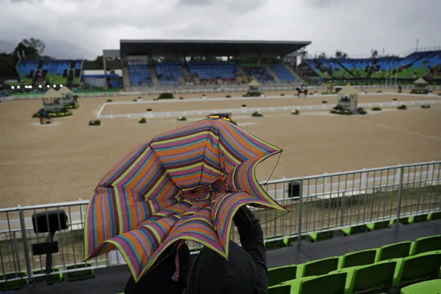 Wind blows open an fan's umbrella during the equestrian dressage competition at the 2016 Summer Olympics in Rio de Janeiro, Brazil, Wednesday, August 10, 2016. (Photo by John Locher/AP Photo)