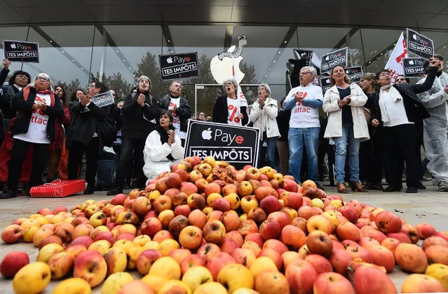 Activists of the Association for the Taxation of financial Transactions and Citizen' s Action (ATTAC) stand next to apples and signs reading “pay your taxes” displayed during a protest outside an Apple shop on the release day of the new iPhone X in Aix- en- Provence, southern France on November 3, 2017. (Photo by Anne-Christine Poujoulat/AFP Photo)