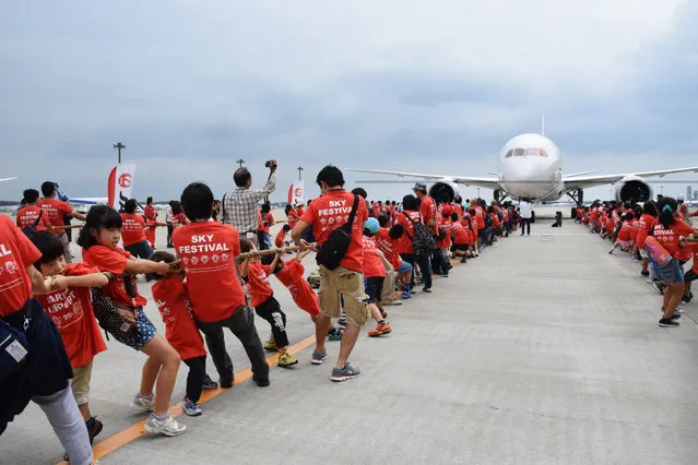 A 166 elementary school children and their 112 parents pull a Boeing 787 jetliner at the Narita International airport in Narita, suburb of Tokyo on September 13, 2015. (Photo by AFP Photo/JIJI Press)