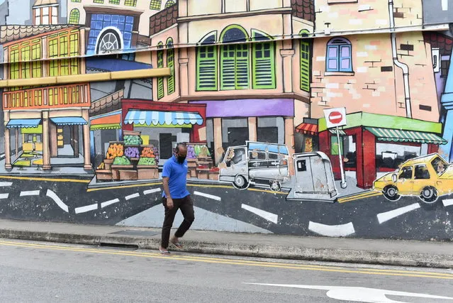 A man with a facemask walks past a wall mural in Singapore’s Little India district on Saturday, May 16, 2020. Wearing of facemarks is mandatory for everyone who goes outside their homes to control the spread of the coronavirus in the city state. Singapore has reported more than 27,000 COVID-19 cases, with 90% of the cases linked to foreign workers dormitories, but it has a low fatality rate of 21 deaths. (Photo by Y.K. Chan/AP Photo)