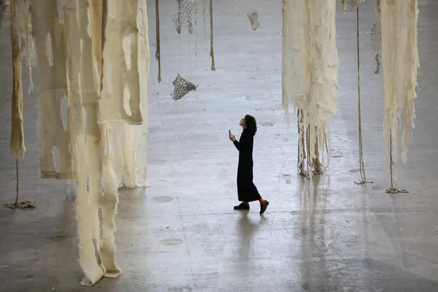 A gallery assistant looks at the latest Hyundai Commission for Tate Modern's Turbine Hall, by Chilean artist Cecilia Vicuna displayed at the museum, in London, on October 10, 2022. Chilean artist Cecilia Vicuna is best known for her radical textile sculptures combing natural materials and traditional craft. Through her art and poems she seeks to preserve and pay tribute to her country’s indigenous history and culture as well as pressing concerns over ecology, community and social justice. (Photo by Isabel Infantes/AFP Photo)