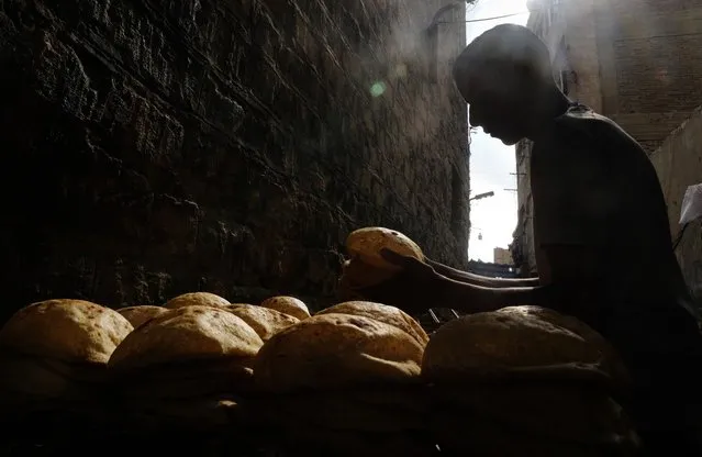 A baker stacks loaves of Egyptian traditional “baladi” flatbread outside a bakery, in the Old Cairo district of Cairo, Egypt, September 8, 2022. For decades, millions of Egyptians have depended on the government to keep basic goods affordable. But a series of shocks to the global economy and Russia's invasion of Ukraine have endangered the social contract in the Middle East's most populous country, which is also the world's biggest importer of wheat. It is now grappling with double-digit inflation and a steep devaluation of its currency. (Photo by Amr Nabil/AP Photo)