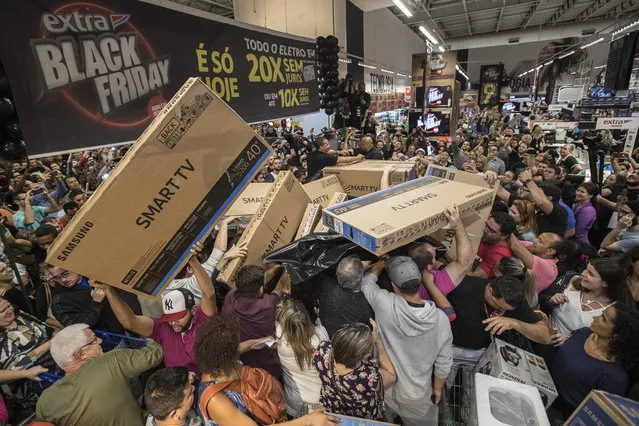 Dozens of Brazilians reach for television sets in a store of Sao Paulo, Brazil, 23 November 2017, during the 'Black Friday' discount deals. According to reports, at least 68 percent of the Brazilians purchased retail items during Black Friday, a number that compared with the 61 percent of last year, shows a slow increase of the economy. (Photo by Sebastiao Moreira/EPA/EFE)