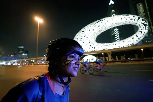 A bicyclist with a bike painting on her face rides past the Museum of the Future, in Dubai, United Arab Emirates, Sunday, November 6, 2022. Thousands of people take part in annual Dubai Ride on the skyscraper-lined super highway that cuts through the center of the city. (Photo by Kamran Jebreili/AP Photo)