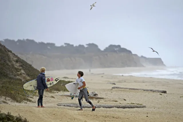 Surfers gather their belongings after being asked to leave by security patrolling the beach at Half Moon Bay State Park in Half Moon Bay, Calif., Friday, July 3, 2020. California Gov. Gavin Newsom ordered the parking lots of state beaches to close for the Fourth of July weekend to help prevent the spread of the coronavirus. Half Moon Bay added to the closure by restricting visitors access to the beach. (Photo by Jose Carlos Fajardo/Bay Area News Group via AP Photo)