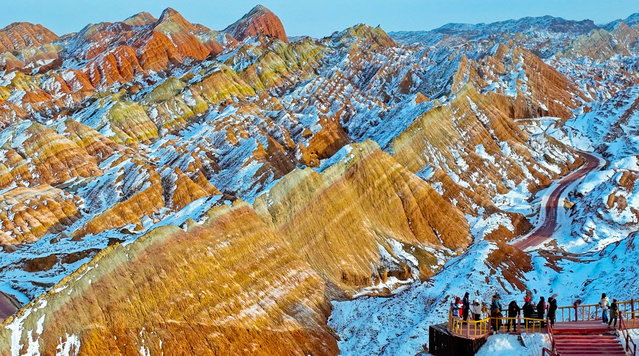 Tourists enjoy the magnificent scenery of the Qicai Danxian scenic area blanketed with snow during the Spring Festival holiday on January 30, 2025 in Zhangye, Gansu Province of China. Danxia is a special landform formed from reddish sandstone. (Photo by VCG/VCG via Getty Images)