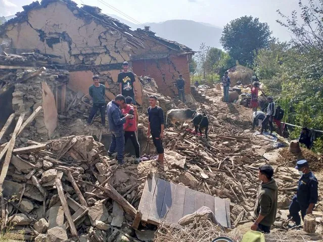 Nepalese villagers stand amidst the debris of their mudhouses after an earthquake in Doti district, Nepal, Wednesday, Noember.9, 2022. A government official said the quake has killed at least six people while they were asleep in their houses in a remote, sparsely populated mountain village. (Photo by Dil Bahadur Singh/AP Photo)