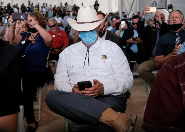 Midland County Sheriff David Criner checks his mobile phone as he gathers to hear U.S. President Donald Trump deliver remarks during a tour of the Double Eagle Energy Oil Rig in Midland, Texas, U.S., July 29, 2020. (Photo by Carlos Barria/Reuters)