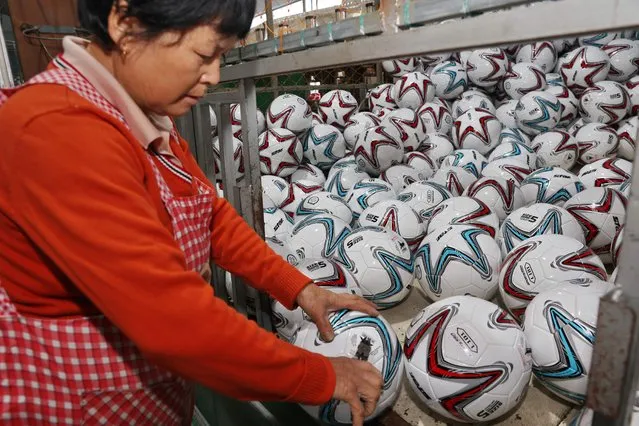 A worker checks footballs at a factory in Nantong in China's eastern Jiangsu province on November 29, 2022. (Photo by AFP Photo/China Stringer Network)