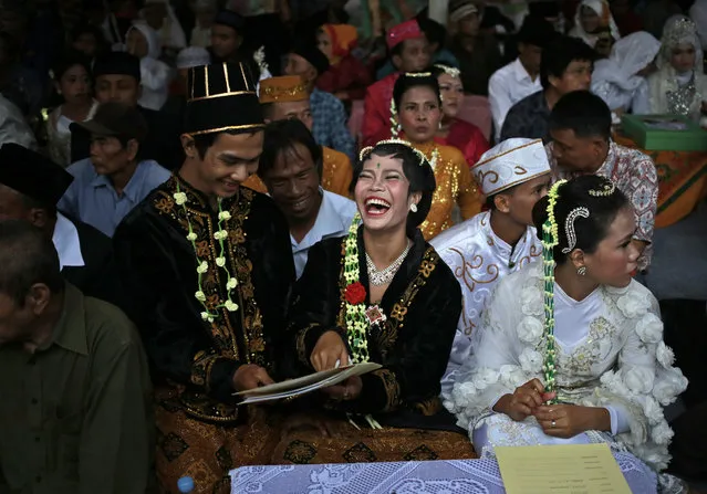 A bride and groom react to their marriage documents during a mass wedding held in celebration of the New Year in Jakarta, Indonesia, Sunday, December 31, 2017. Hundreds of couples took part in the mass marriage held by the city government to help the poor who were unable to afford a proper wedding. (Photo by Dita Alangkara/AP Photo)