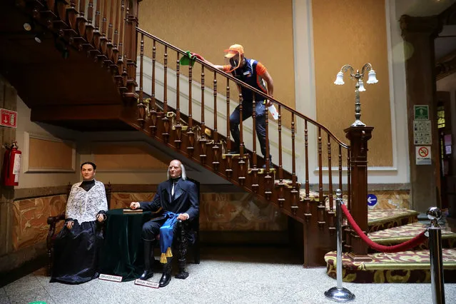 An employee cleans the handrail of a staircase over the wax figures of Catholic priest and leader of the Mexican War of Independence Miguel Hidalgo and Josefa Ortiz de Dominguez during the start of gradual reopening of commercial activities, as the coronavirus disease (COVID-19) outbreak continues, at the wax museum in Mexico City, Mexico, August 11, 2020. (Photo by Edgard Garrido/Reuters)