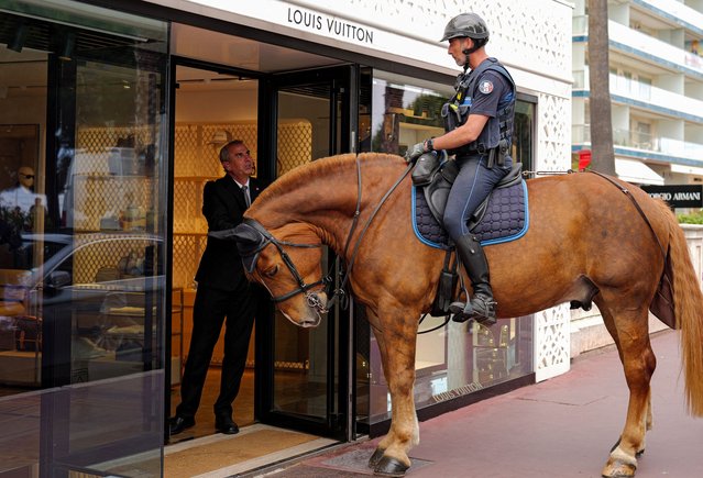 A police officer of Cannes' municipal police equestrian brigade speaks to an employee of Louis Vuitton during a patrol on the Boulevard de la Croisette, in Cannes, southeastern France, on May 11, 2025, ahead of the 78th Cannes Film Festival. The Cannes Film festival will take place from May 13th to May 24, 2025. (Photo by Valery Hache/AFP Photo)